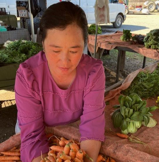 A grower sorting fresh carrots at a market table